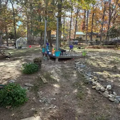 The same backyard cleared, with a new stone dry creek bed and fresh plantings, in Greenville, SC