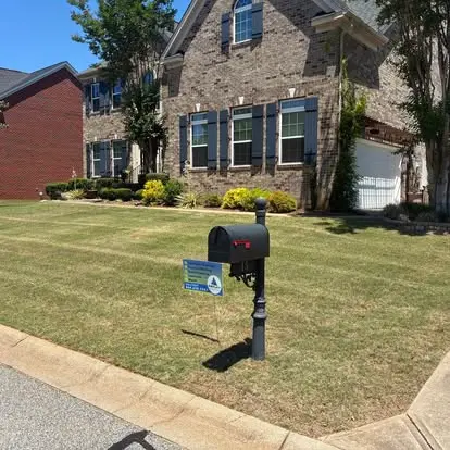 Brick home with a freshly maintained front lawn and an Amplify Outdoor Solutions yard sign in Greenville, SC