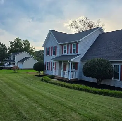 White home with red shutters, a green lawn, and two neatly shaped round shrubs in Greenville, SC